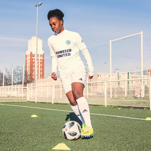 A player dribbling a ball through a cone drill.