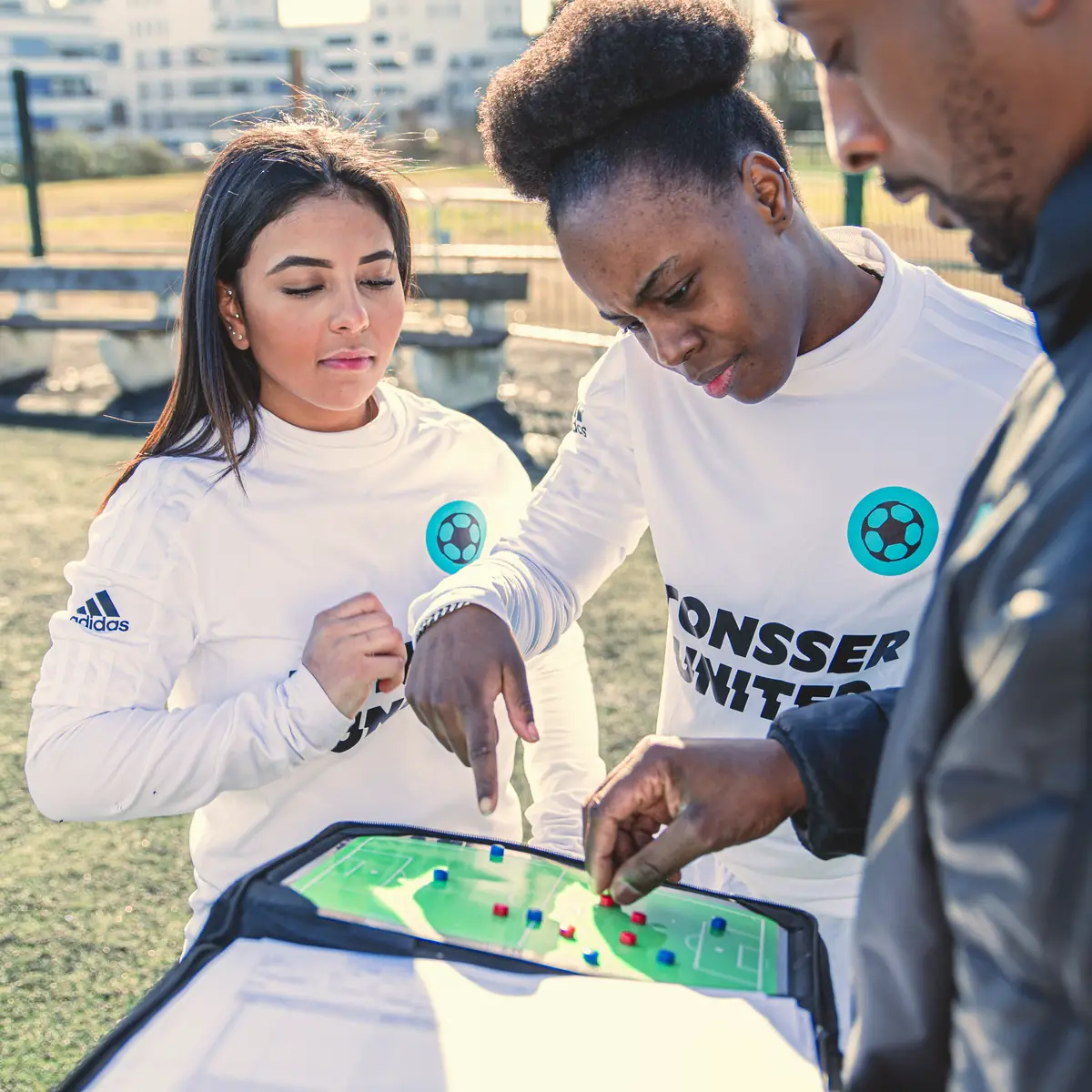 A coach and two Tonsser United players planning a move on a tactics board.